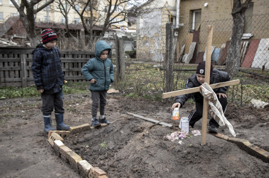 Children offering food to their mothers grave site following Russias withdraw. 