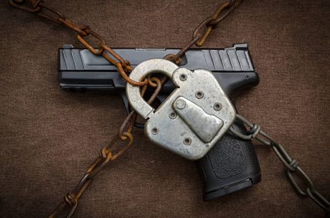 Pistol behind lock and chains symbolic of gun control.